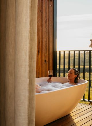 Couple enjoying bath and wine from balcony at Cupitt's Estate Villas, Ulladulla